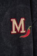 Detalle del bordado chili junto a la M en hoodie negro washed