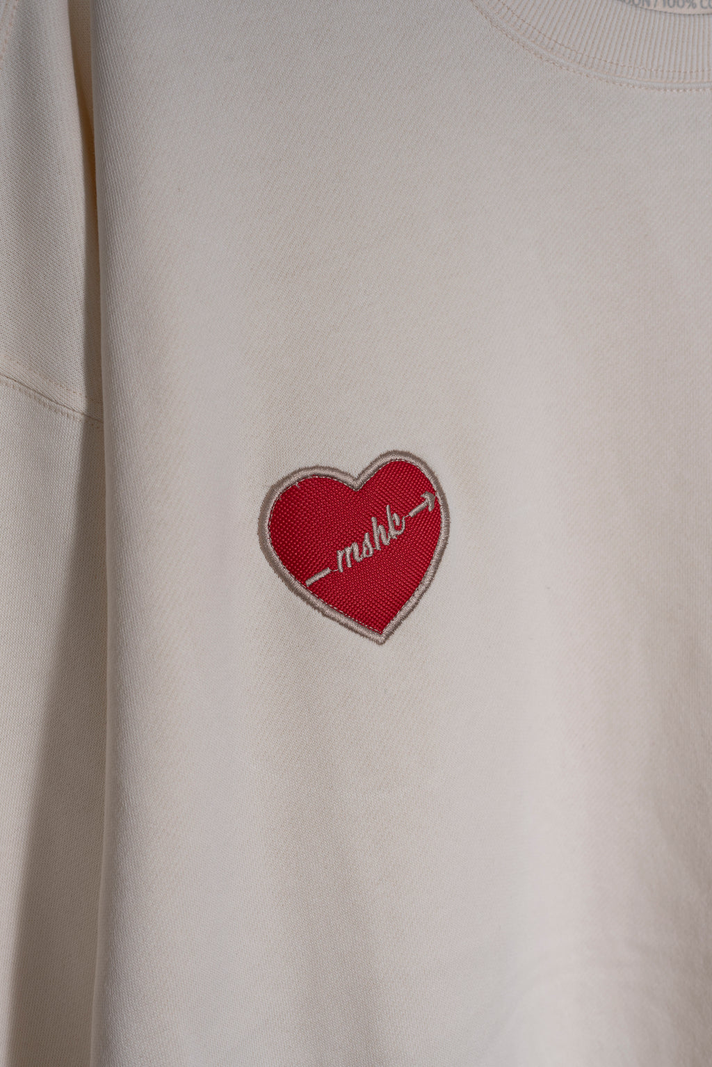 Detalle del bordado trébol en buzo vainilla Lucky Heart