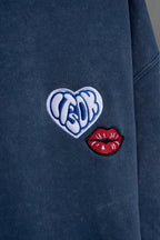 Detalle del bordado labios en hoodie azul washed It's OK