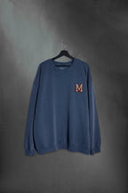 Buzo azul washed oversize con M bordada estilo varsity de Mushkana